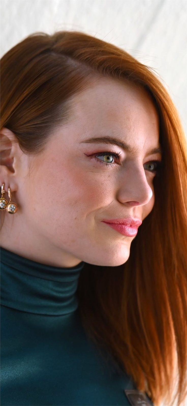 a woman with long red hair wearing earrings