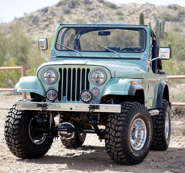 a green jeep is parked in the desert