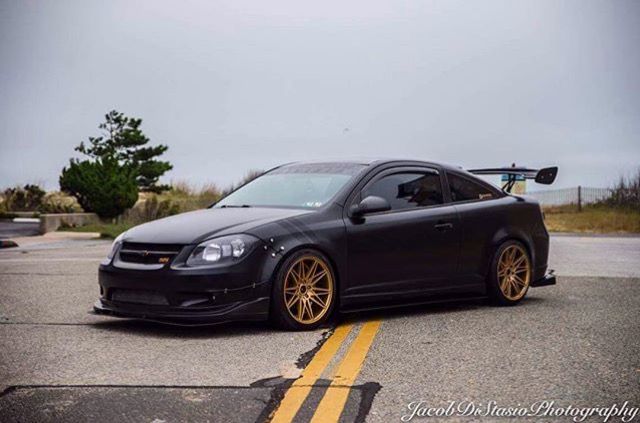 a black car with gold rims parked on the street