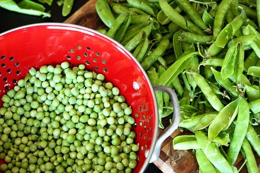 peas are in a red colander next to green beans