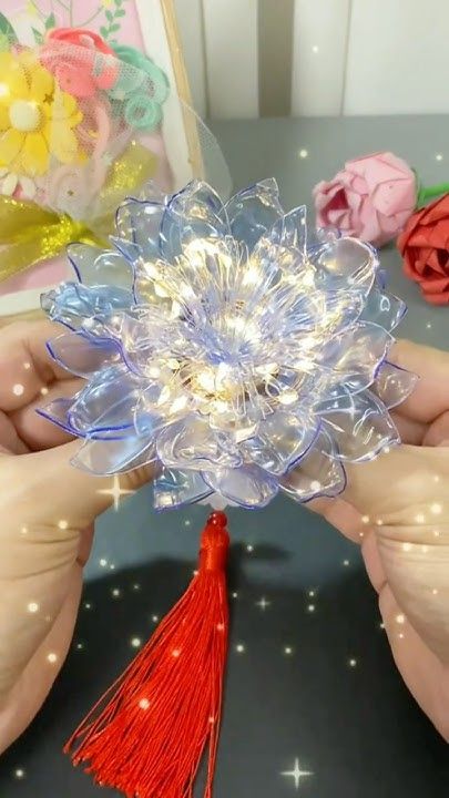 two hands are holding a plastic flower with lights on it