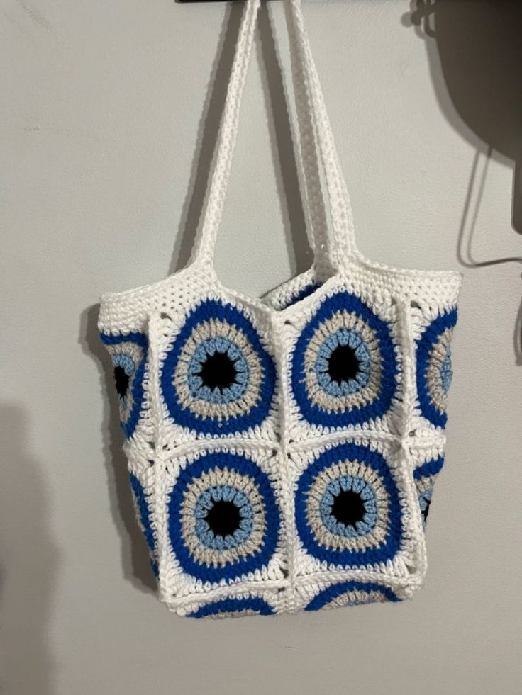 a blue and white crocheted bag hanging from a hook