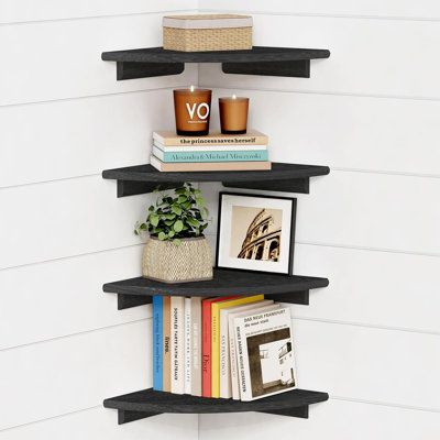 three black shelves with books and pictures on them in the corner of a white room