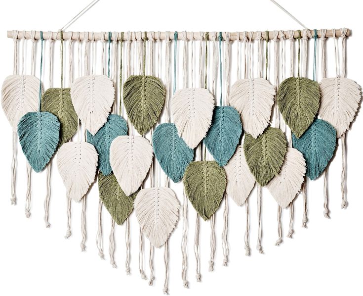 a white and blue wall hanging with green leaves on the front, along with two strings attached to it