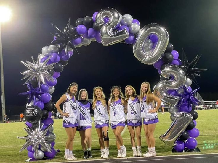 the cheerleaders are posing for a photo in front of an arch made out of balloons