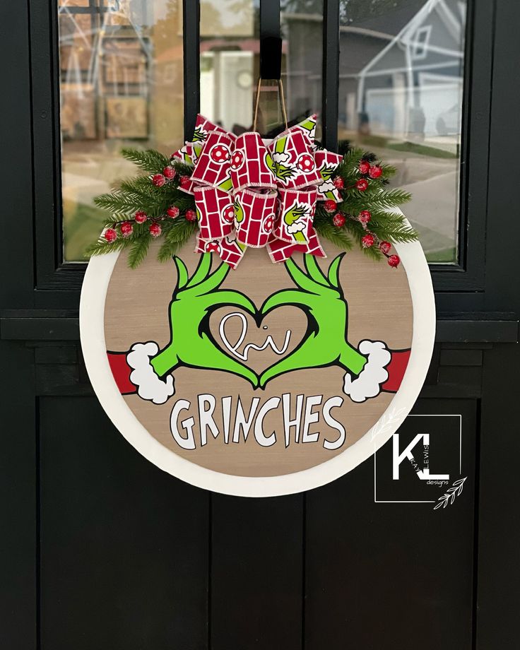 the grinches door hanger is decorated with red bows and green hands holding a heart