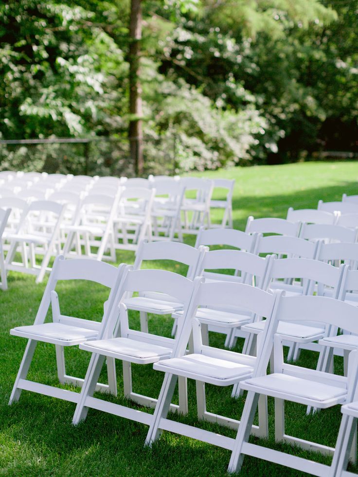 rows of white folding chairs sitting in the grass