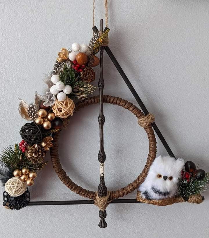 a christmas wreath hanging on the wall with an owl and pineconi ornament