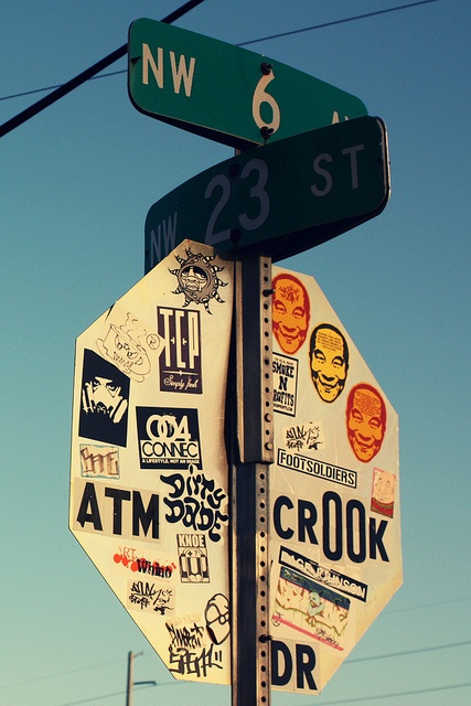 a stop sign covered in stickers under a blue sky