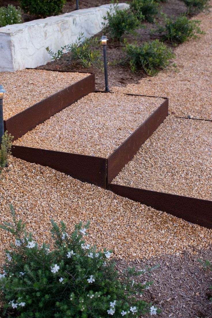 a set of steps leading up to the top of a rock garden area with gravel and flowers