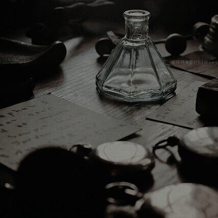 an empty glass bottle sitting on top of a wooden table next to other dishes and utensils