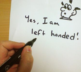 a hand holding a pen writing on a piece of paper with the words yes, i am left handed