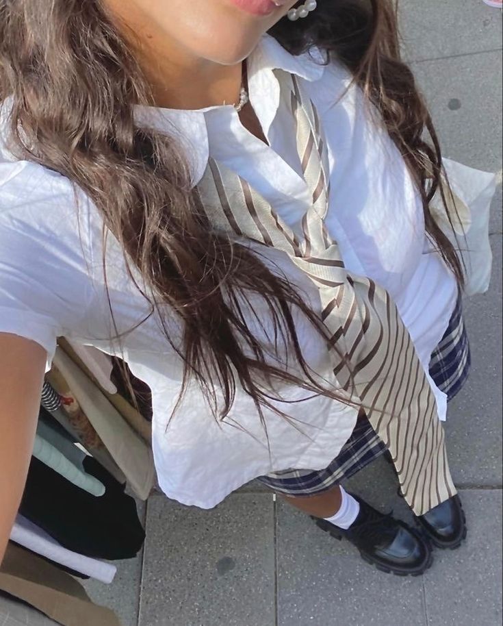 a woman in white shirt and tie sitting on the ground