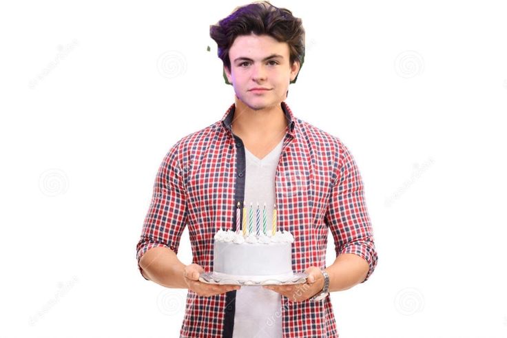 a young man holding a cake with candles on it in front of his face and looking at the camera