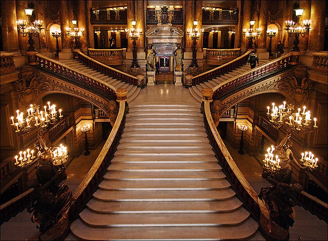 an ornate staircase with chandeliers and lights in a large building that looks like a palace