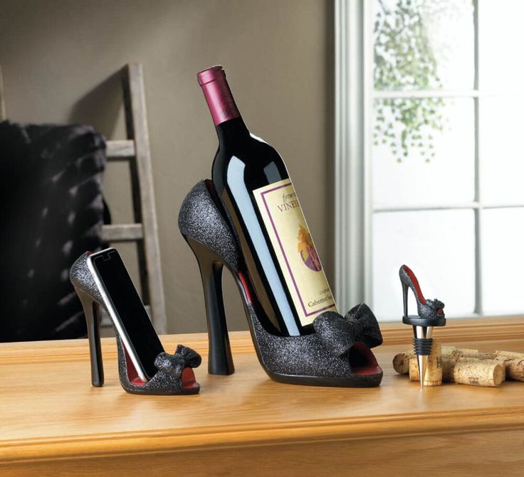 a bottle of wine sitting on top of a table next to two shoes and a phone