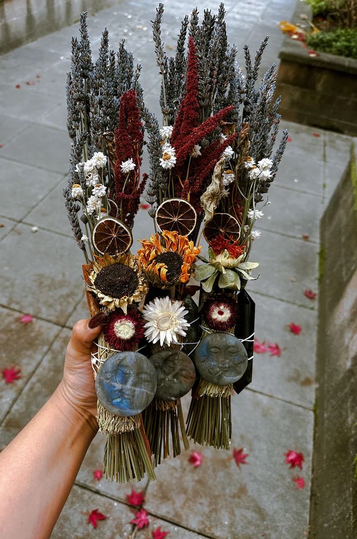 a person holding flowers in their hand on the sidewalk