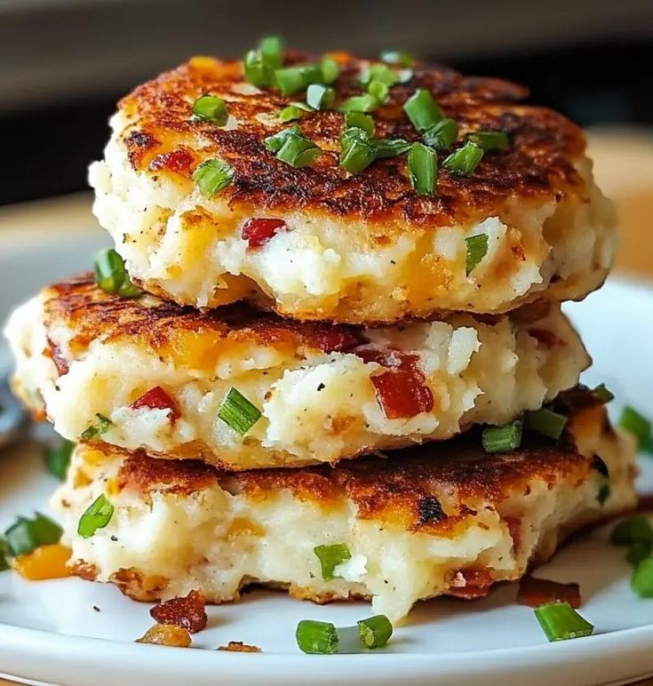 three crab cakes stacked on top of each other with scallions and green onions