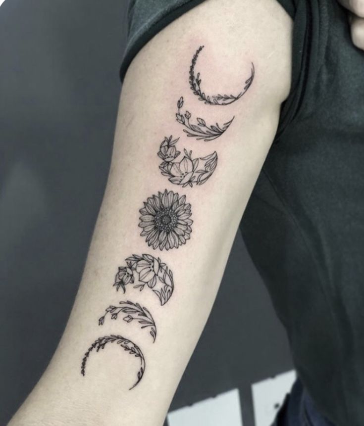 a woman's arm with flowers and crescents on it, in black ink