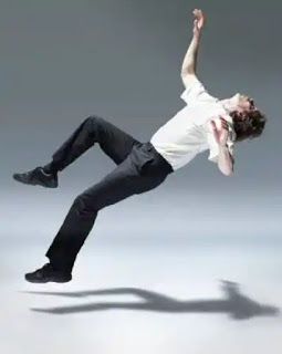 a man in white shirt and black pants doing a trick on skateboard with shadow