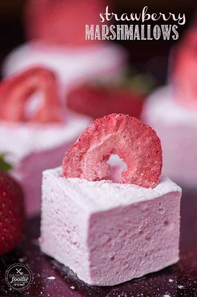 strawberry marshmallows on a plate with strawberries in the background and text overlay that reads strawberry marshmallows