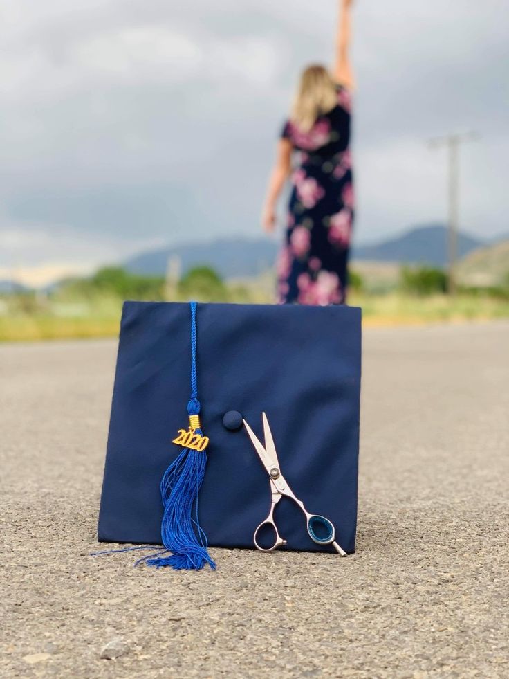 a graduation cap and pair of scissors sitting on the ground in front of a woman