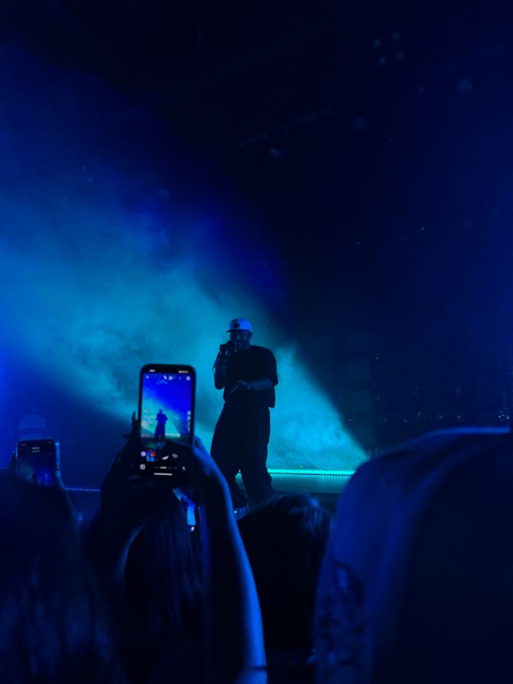 a man standing on top of a stage holding a cell phone in front of him