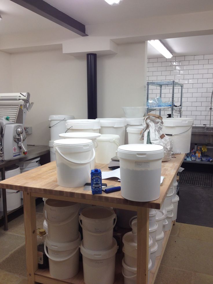 several white buckets sitting on top of a wooden table in a room filled with appliances