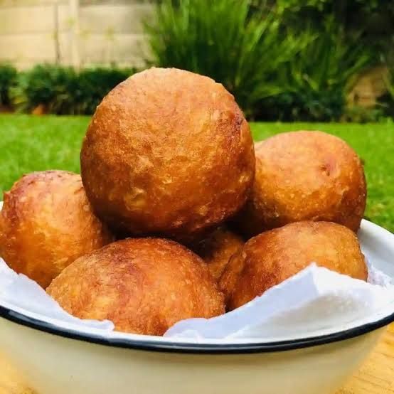 a bowl full of doughnut holes sitting on top of a wooden table in the grass