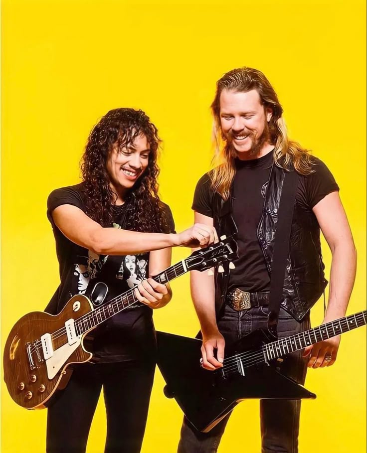 two people standing next to each other with guitars