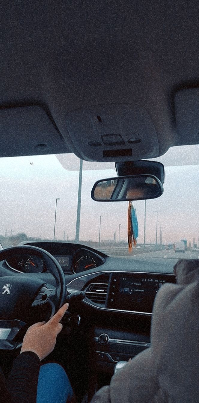 a person driving a car on the road in front of other cars with their hands on the steering wheel