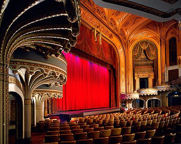 an empty theater with red curtains and seats