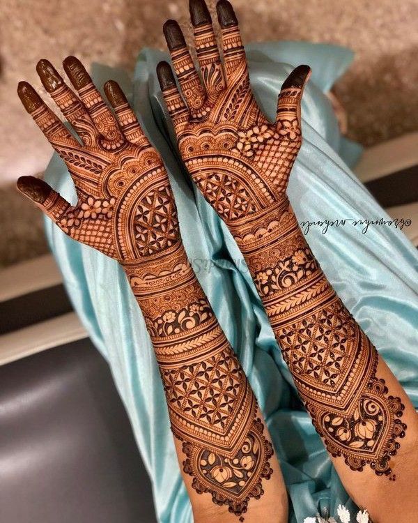 two hands with henna tattoos on them, one is showing off the intricate design