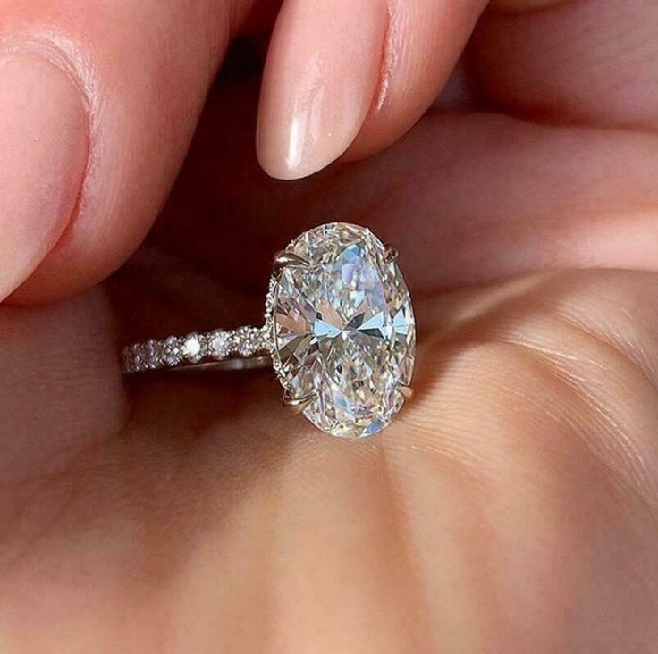 a close up of a person holding a ring with a large diamond in the middle