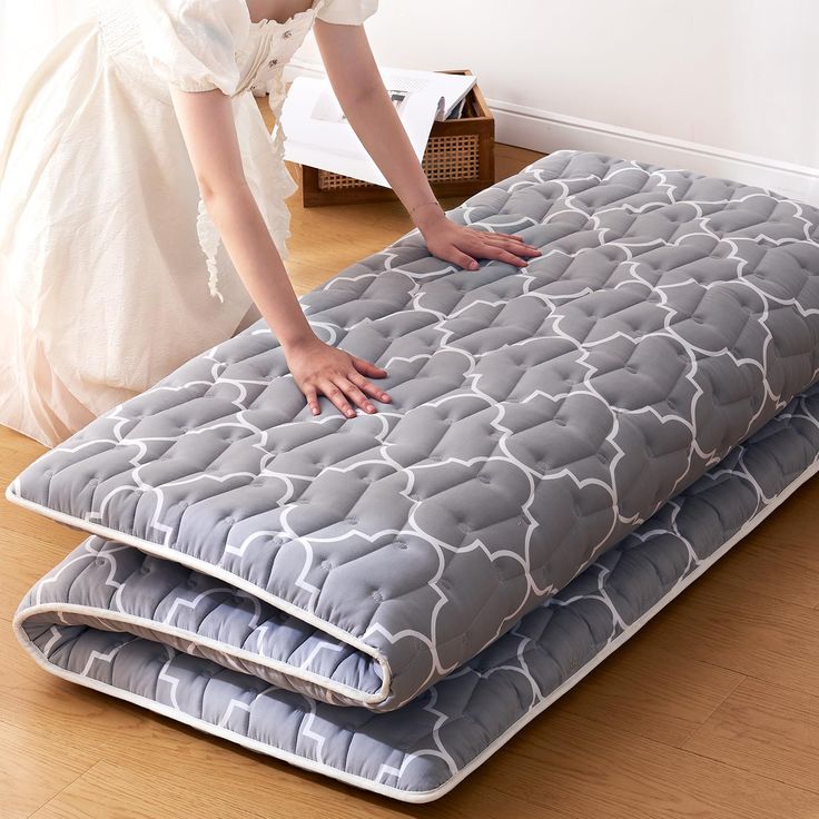 a woman is placing her mattress on the floor