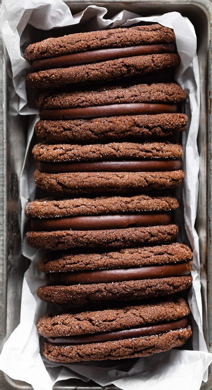 chocolate cookies are stacked on top of each other in a baking pan with parchment paper