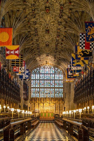 the interior of a large cathedral with many flags hanging from it's ceiling and stained glass windows