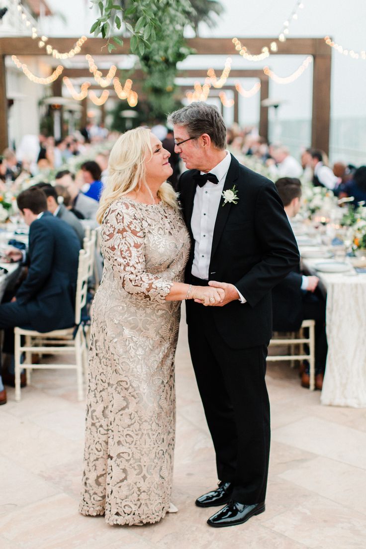 a man and woman standing next to each other in front of tables with white linens