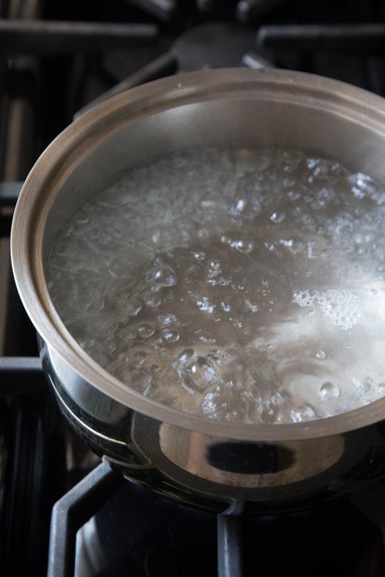 boiling water in a pot on top of an oven burner with the lid open