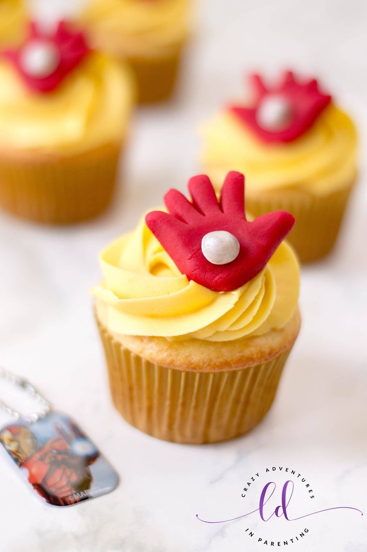 cupcakes with yellow frosting and red decorations