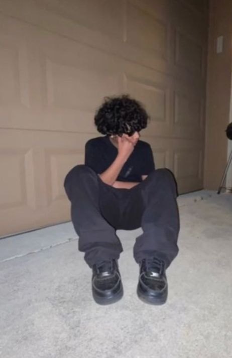 a person sitting on the floor in front of a garage door with their hands to their face