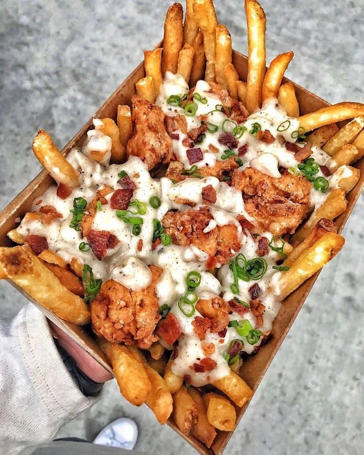 a box filled with chicken and french fries covered in ranch dressing on top of a table