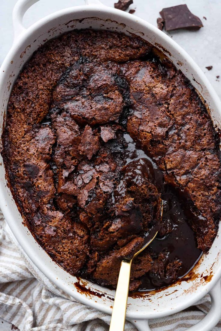 a chocolate cake in a white dish with a spoon