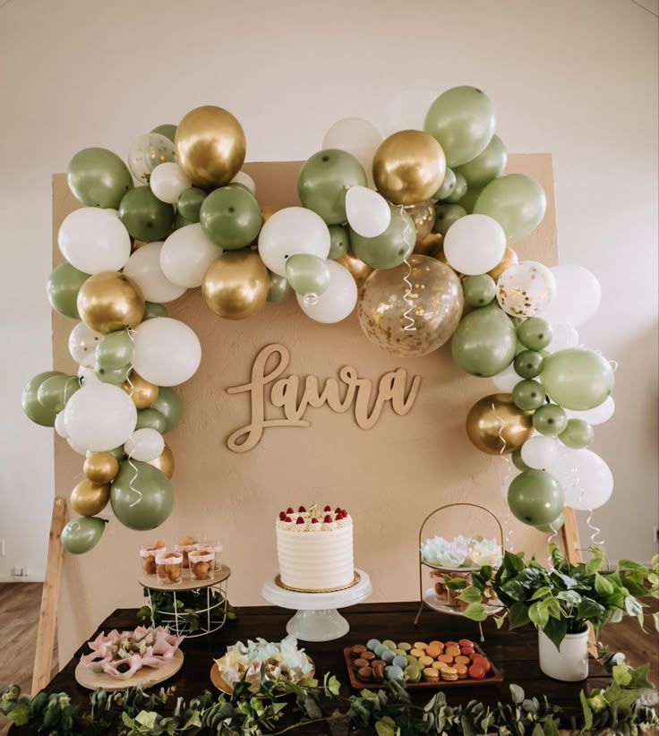 the dessert table is decorated with balloons and greenery