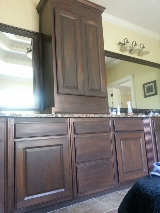 a bathroom with wooden cabinets and marble counter tops in the middle, along with a large mirror on the wall