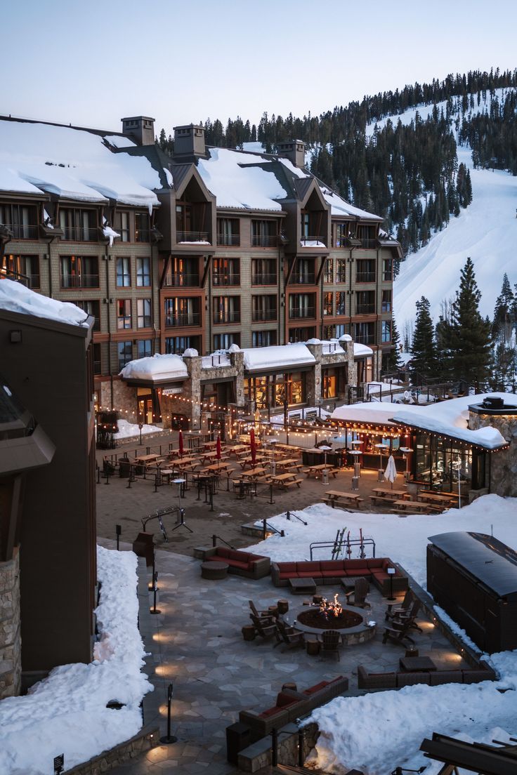 the resort is lit up at night in the snow covered mountainside area, surrounded by trees and buildings