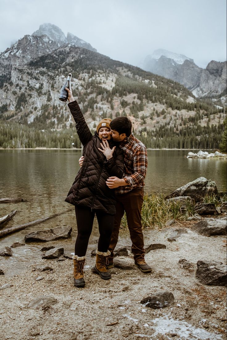 a man and woman taking a selfie in front of a mountain lake