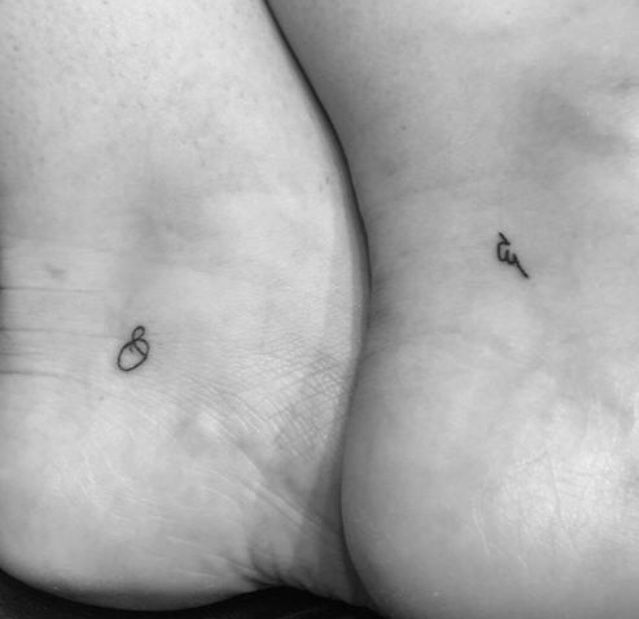 two people with small tattoos on their butts, one is holding the other's leg