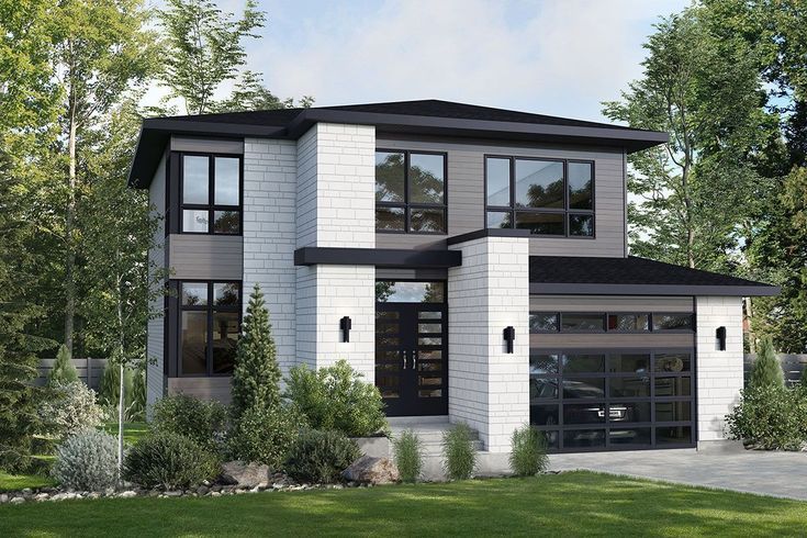 a two story house with lots of windows and grass in front of the garage area