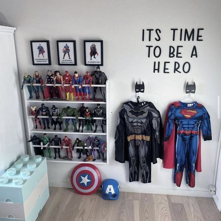 a room filled with toys and pictures on the wall next to a shelf full of batman costumes